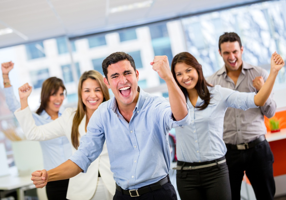 Five people in business casual clothing facing the camera and making corny poses